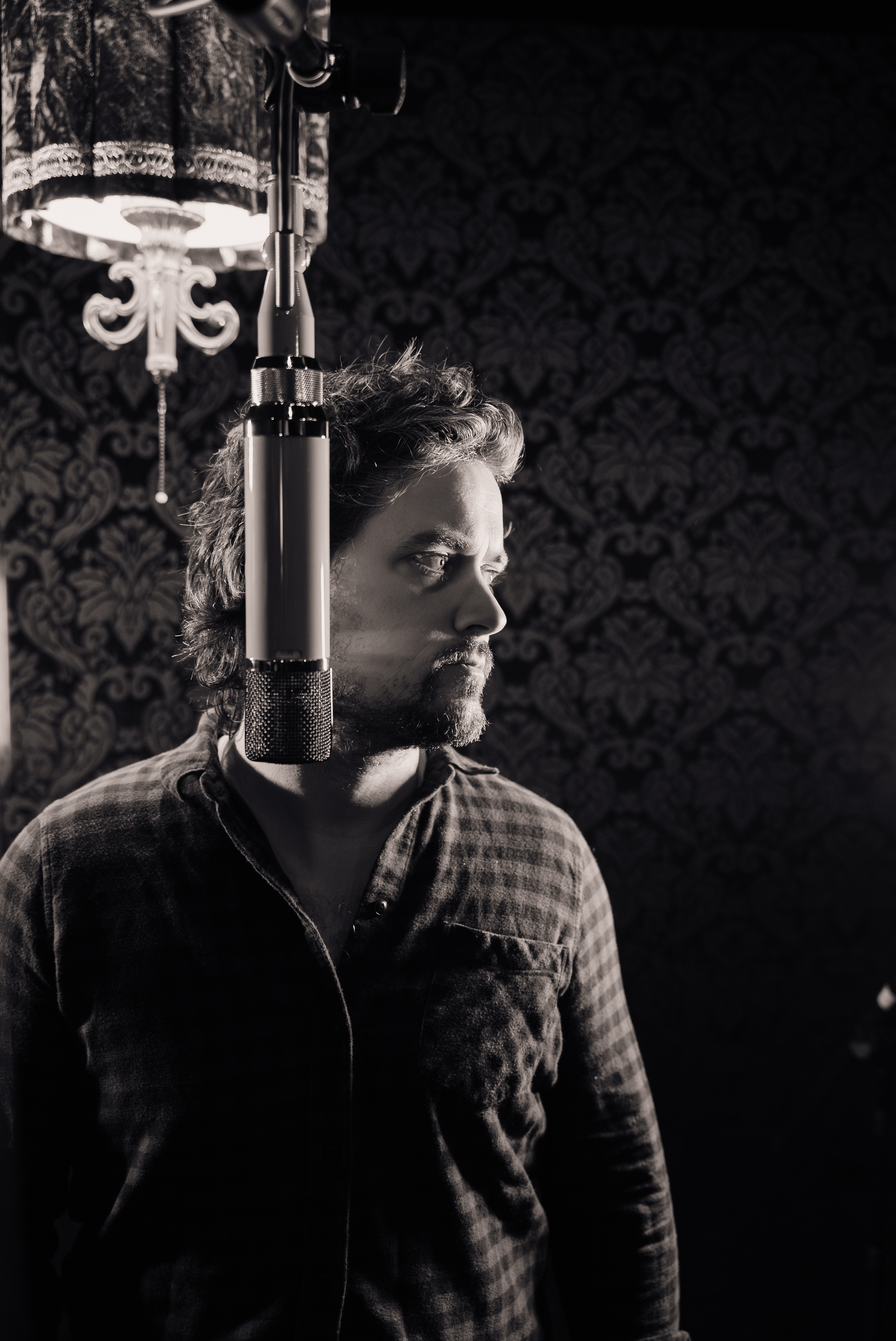 Kingston in a studio beside a suspended microphone and lamp